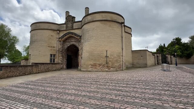 Historical stone gatehouse entrance of nottingham castle with medieval architecture and cobblestone forecourt on overcast day.