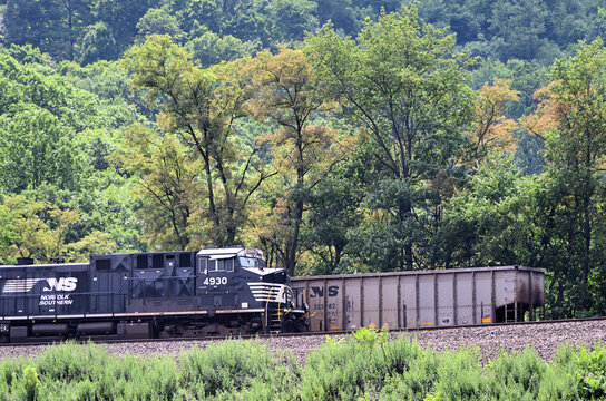 A Norfolk Southern Railway locomotive leads an eastbound freight train down Horseshoe Curve by the end of a westbound empty coal train straining upgrade around the curve in western Pennsylvania.