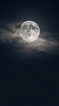 Majestic full moon illuminated against a dramatic dark sky, peeking through wispy, atmospheric clouds, showcasing the serene beauty of the nocturnal heavens