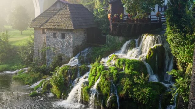 Picturesque old wooden watermill houses beside flowing waterfalls in Rastoke village Croatia at sunrise during soft morning light.