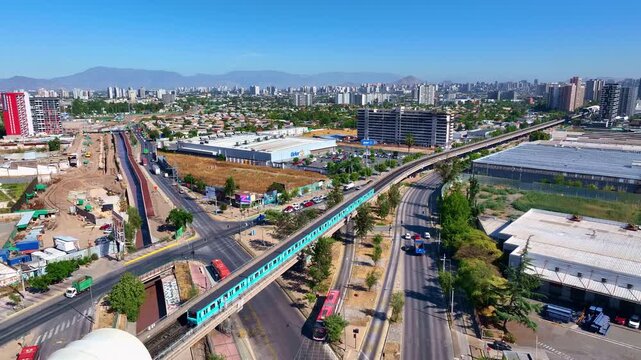 Aerial view of modern passenger train moving along elevated tracks in Santiago city urban landscape.