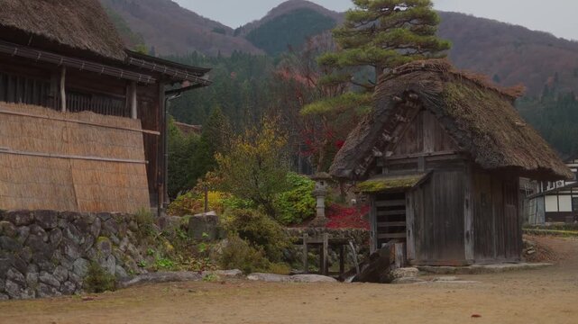 Ancient watermill spinning near traditional thatched roof houses in historical Shirakawa-go village Japan.