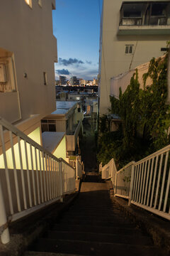 夕暮れの空と明かりの灯る街へ続く住宅の間を下る階段