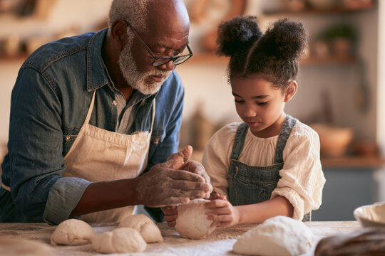 Grandfather and young granddaughter preparing dough together in a warm kitchen, capturing family bonding, baking, learning, tradition and joyful intergenerational connection.