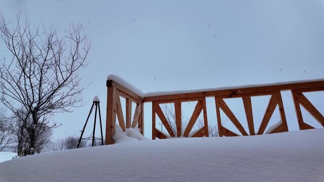 Low angle view of falling snow on wooden deck railing at winter season.