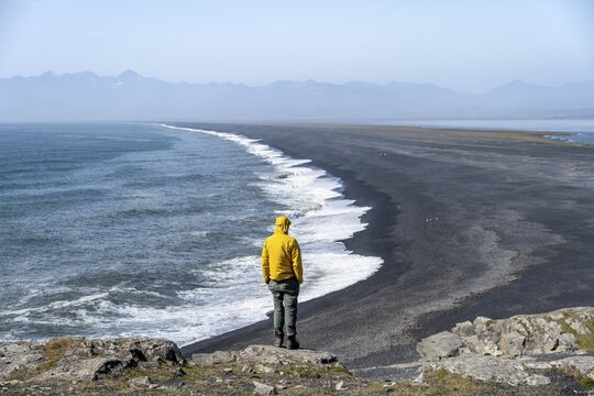 Tourist looking over long black sand beach, Reynisfjara Beach, South Iceland, Iceland