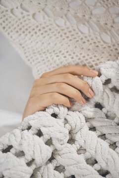 Hand is gently holding soft blanket while resting on comfortable bed at home during evening time. The setting shows a warm and inviting feeling with textiles around