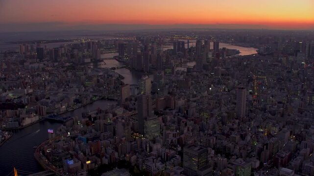 Aerial view of massive city skyline at sunset with rivers and illuminated buildings