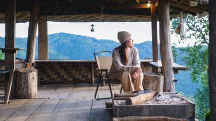 Obraz premium A woman sitting on wooden terrace and looking at nature views