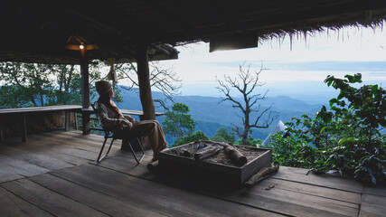 Obraz premium A woman sitting on wooden terrace and looking at nature views