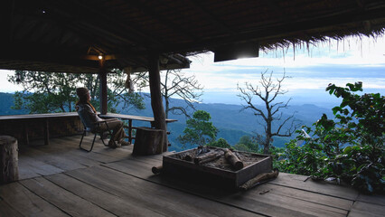 Obraz premium A woman sitting on wooden terrace and looking at nature views