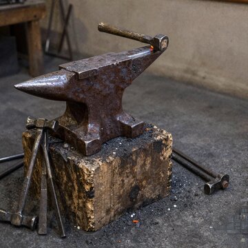 Blacksmith anvil with tongs and hammers on scarred timber block