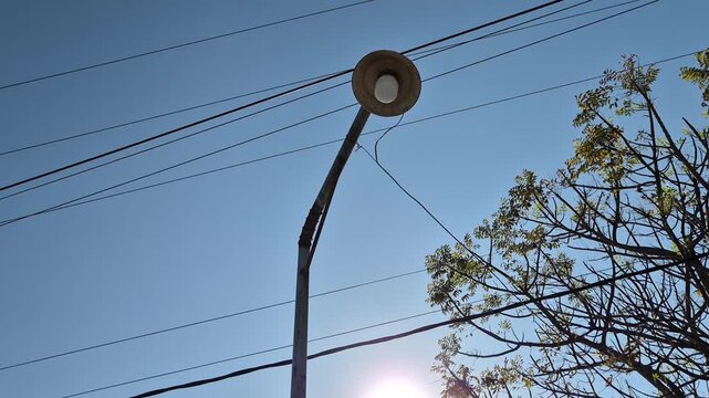 Street Light Pole with Power Lines Against Clear Blue Sky in Daylight