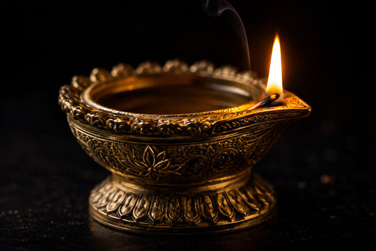 Traditional Ornate Brass Diya with Burning Flame and Smoke on Dark Background
