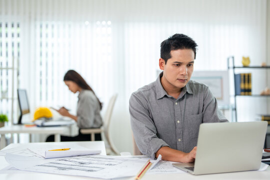 engineer designer or contractor working on drawing plans analyzing structure on laptop computor at construction site office. copy space.