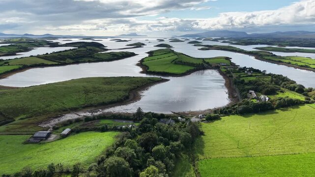 Wide aerial drone view across the Rosbarnagh area of Clew Bay in County Mayo, Ireland. The scenic coastal landscape features numerous green islands, tidal inlets, patchwork farmland, rural houses
