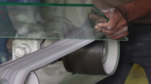 Craftsman processing glass sheet with industrial belt machine