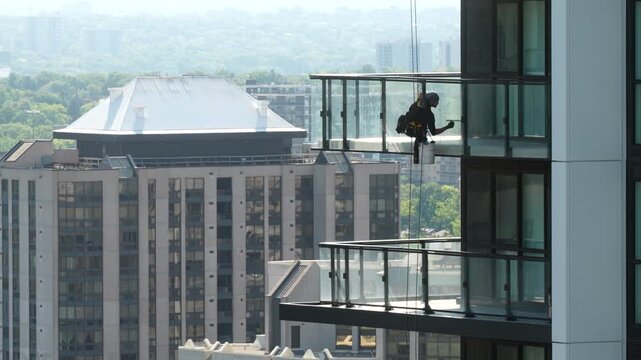 Rope Access Technician Servicing Glass Balcony on High-Rise
