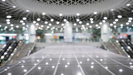 Obraz premium A spacious, modern empty indoor public area with escalators, tiled floor, and bright ceiling lights. Clean and unoccupied architectural space.