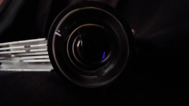 Cinematic macro close-up of a dark camera lens with subtle light reflections and metallic textures on a black background, perfect for technology, optics, and abstract video concepts.