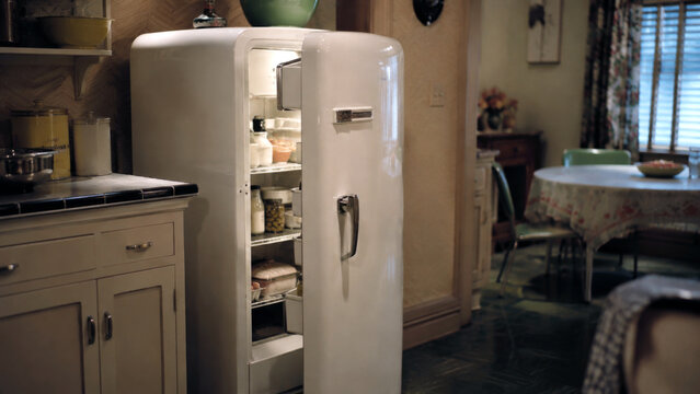 Open vintage refrigerator filled with food in a mid century family kitchen, representing domestic life, food storage and everyday household routine