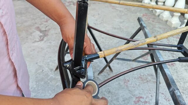 Wrapping Black Electrical Tape Around Bamboo and Metal Joint