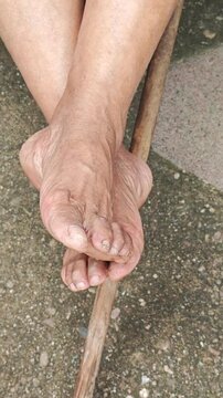 Bare Feet of Adult Woman Resting On Wooden Broom Stick