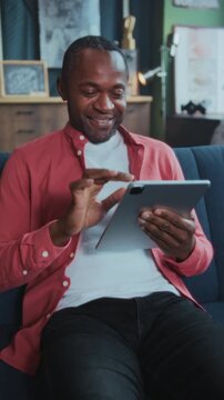 Man sketches designs and manages emails at home, Individual seated on sofa using device for work and creativity