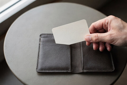Hand Inserting Blank Card into Brown Leather Wallet