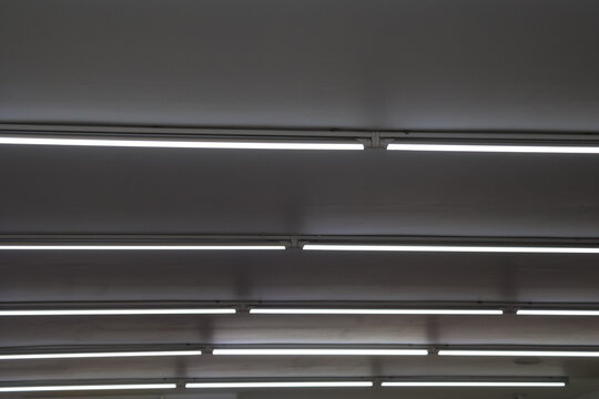 Fluorescent ceiling lights arranged in grid pattern, illuminating modern interior with bright, even lighting, ideal for office and commercial spaces