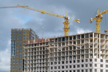 Modern construction site showcasing progress in a bustling urban area with towering cranes against a cloudy sky © beholdereye