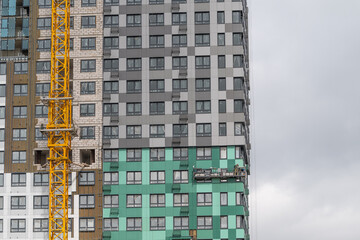 Construction workers skillfully apply finishing touches to a high-rise building under a cloudy sky in a bustling urban area © beholdereye
