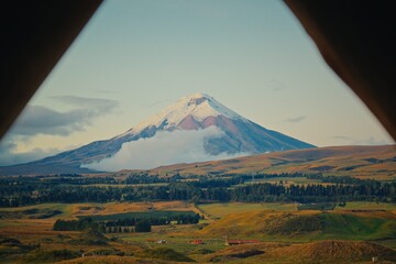 Obraz premium Cotopaxi volcano viewed through triangular frame with rolling hills in Ecuador