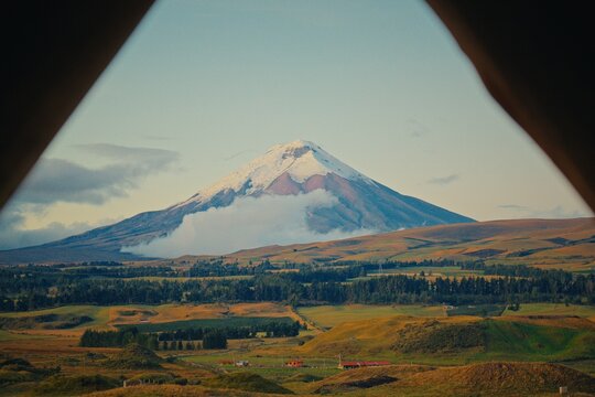 Cotopaxi volcano viewed through triangular frame with rolling hills in Ecuador