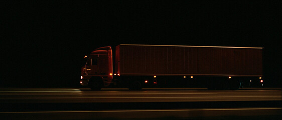 Plakat Red Semi-Truck Driving on Highway at Night with Illuminated Taillights and Headlights