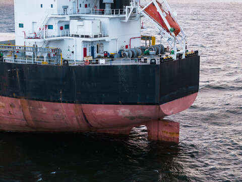 Detailed aerial photograph of the stern section of a large commercial cargo vessel at sea, showing the deck, superstructure, and rudder with textured water.