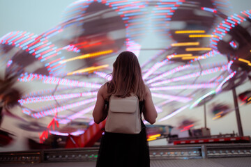  Stressed Woman Having Motion Sickness At Amusement Park. Young female covers her face feeling dizzy near spinning carousel rides at twilight © nicoletaionescu