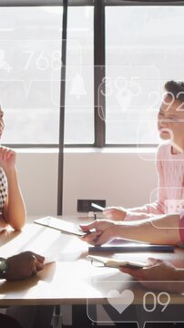 Diverse team discusses under floating social media icon, symbolizing tech integration.