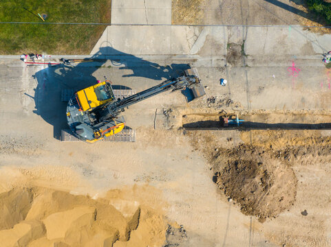 Top-down shot of yellow excavator moving dirt during site work