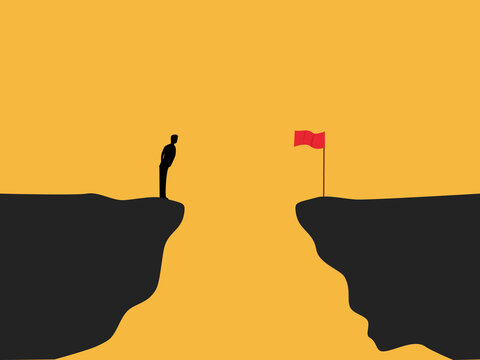 businessman stood on a cliff edge, looking at the red flag