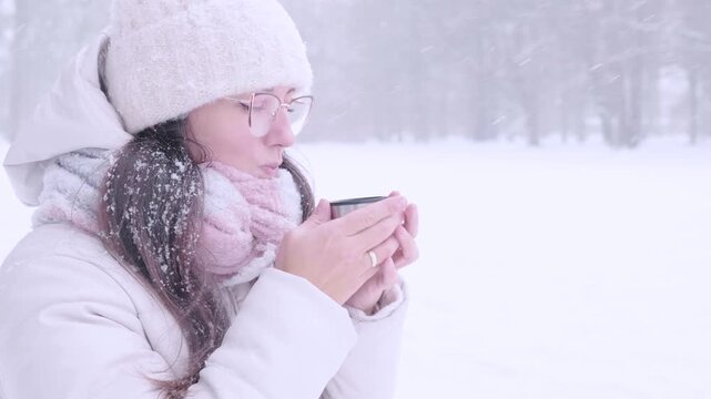 Woman outdoor lifestyle. Female drinking tea during snowfall. Mindful living concept.