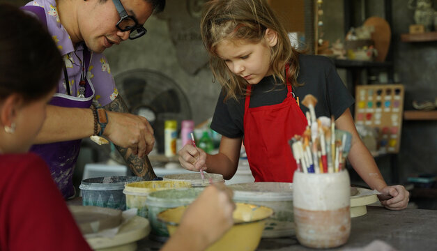 Children shaping clay plates in creative studio during ceramics workshop