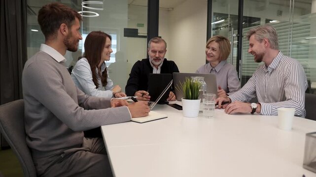 Successful businesspeople working in a coworking space working with laptop discussing strategy and business plan in modern office.