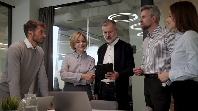 Five business people discussing work together in a modern office