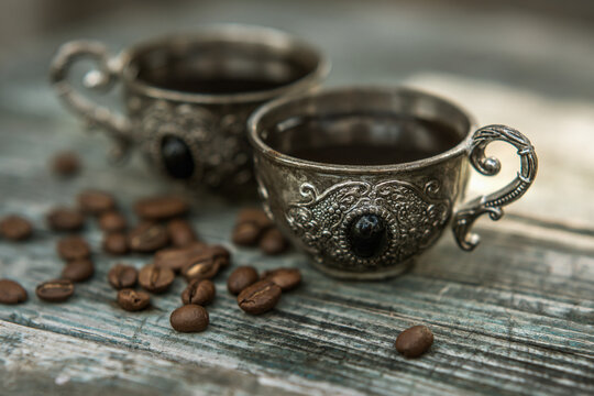 Black coffee in vintage silver cups on wooden background