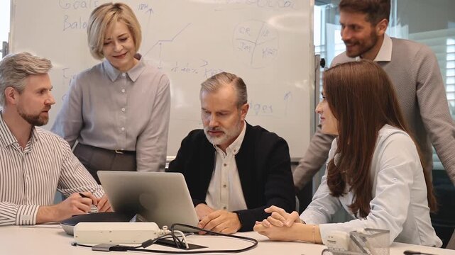 Successful businesspeople working in a coworking space working with laptop discussing strategy and business plan in modern office.