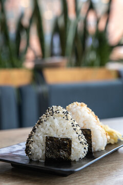 Onigiri or Japanese rice triangle served on the wooden tabletop in the cafe. Kimbab or gimbap - Korean rice triangle. Japanese onigiri sushi. Korean Samgak-gimbap. Selective focus.