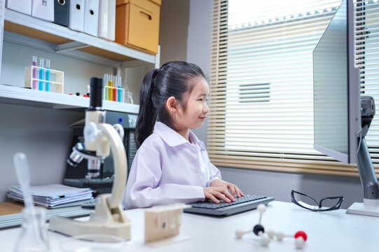 Asian girl student in lab coat using computer in science laboratory for stem education and school learning concepts	