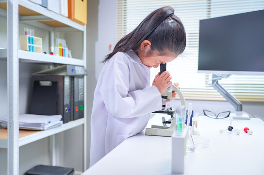 Asian girl student looking through microscope in science laboratory for stem education and biotechnology learning	