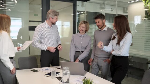 Business people discussing work together using a tablet and laptop taking notes in a modern office